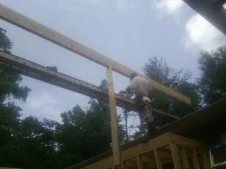 Carpenter setting a ridge beam over a new addition frame — Ice Dam Removal by Roofing Brothers in Zapata