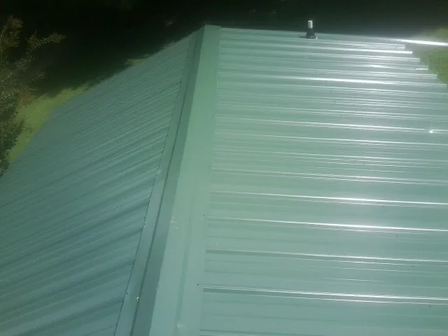 New green metal panels meeting at the ridge of a roof — Flat Roof Repair work by our crew in Zapata