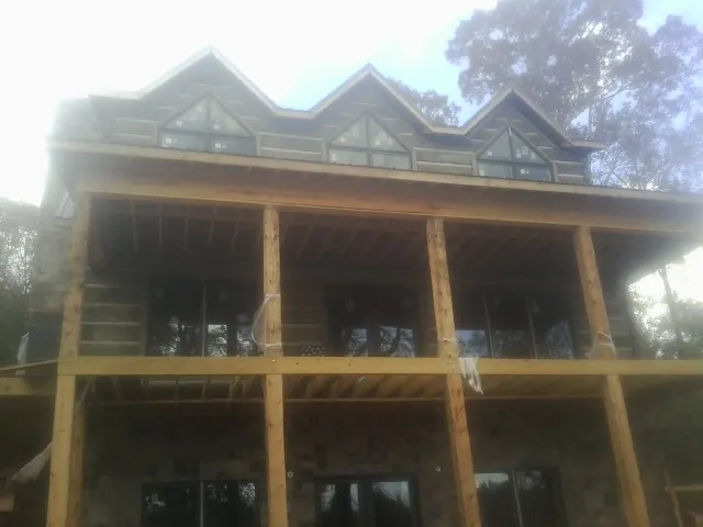 Dormers and porch framing on a large log home under construction — Roof Coating work by our crew in Zapata