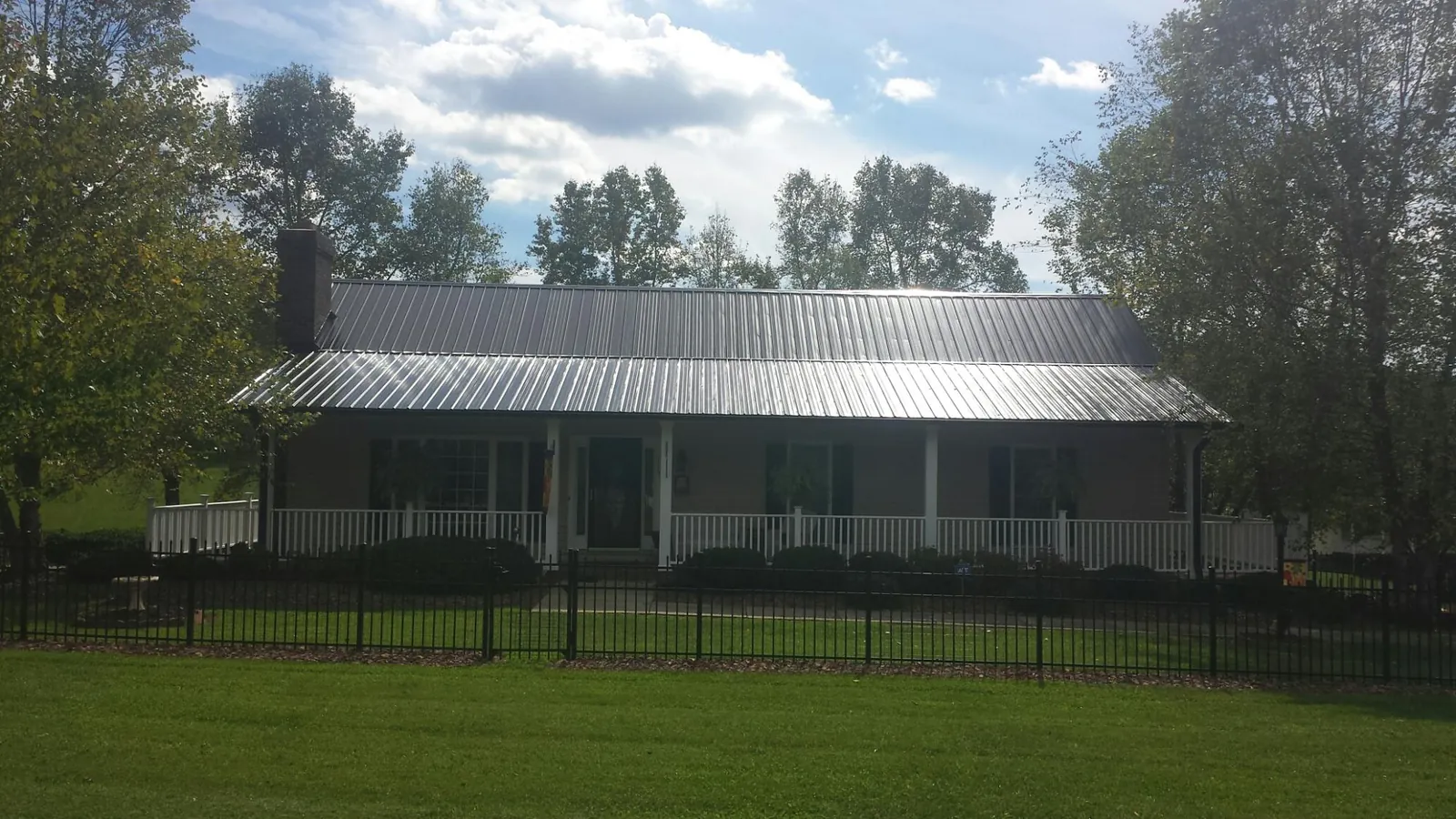 Gray metal roof on a brick ranch with a full width front porch — Gutter Guard Installation work by our crew in Zapata