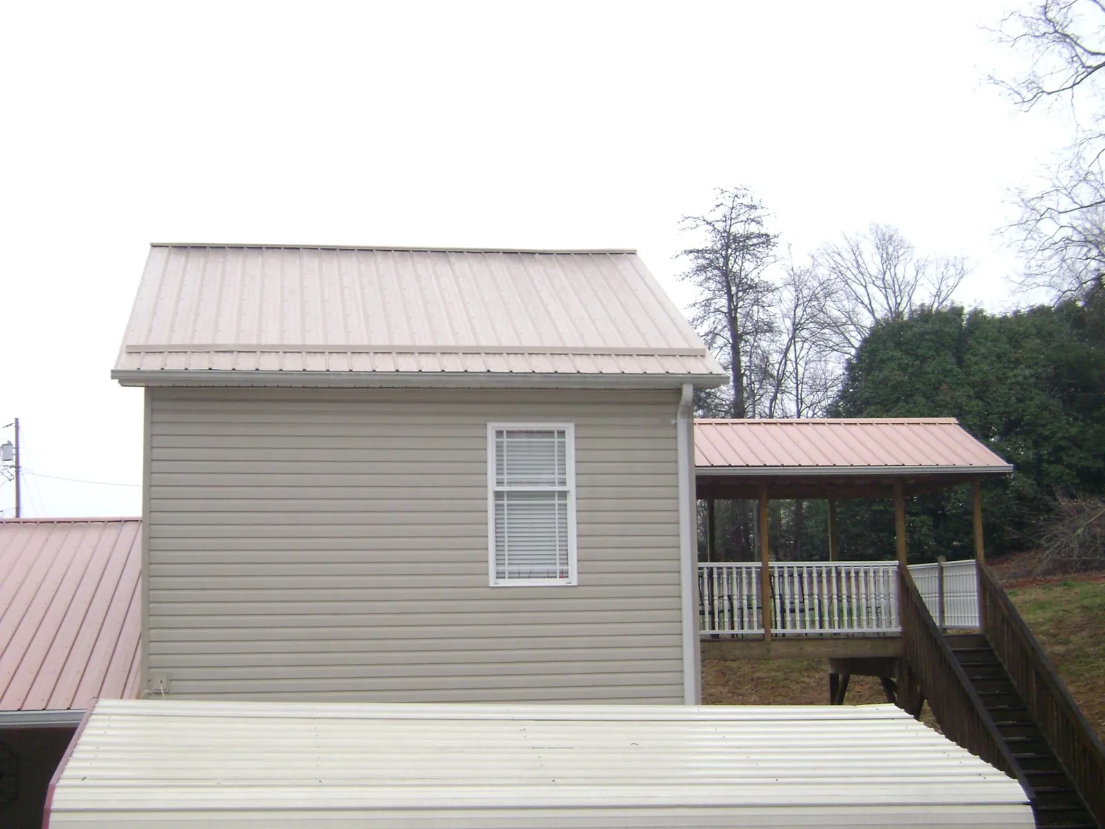 Tan metal roofs on a two story addition and attached porch, from a Roof Replacement job in Zapata