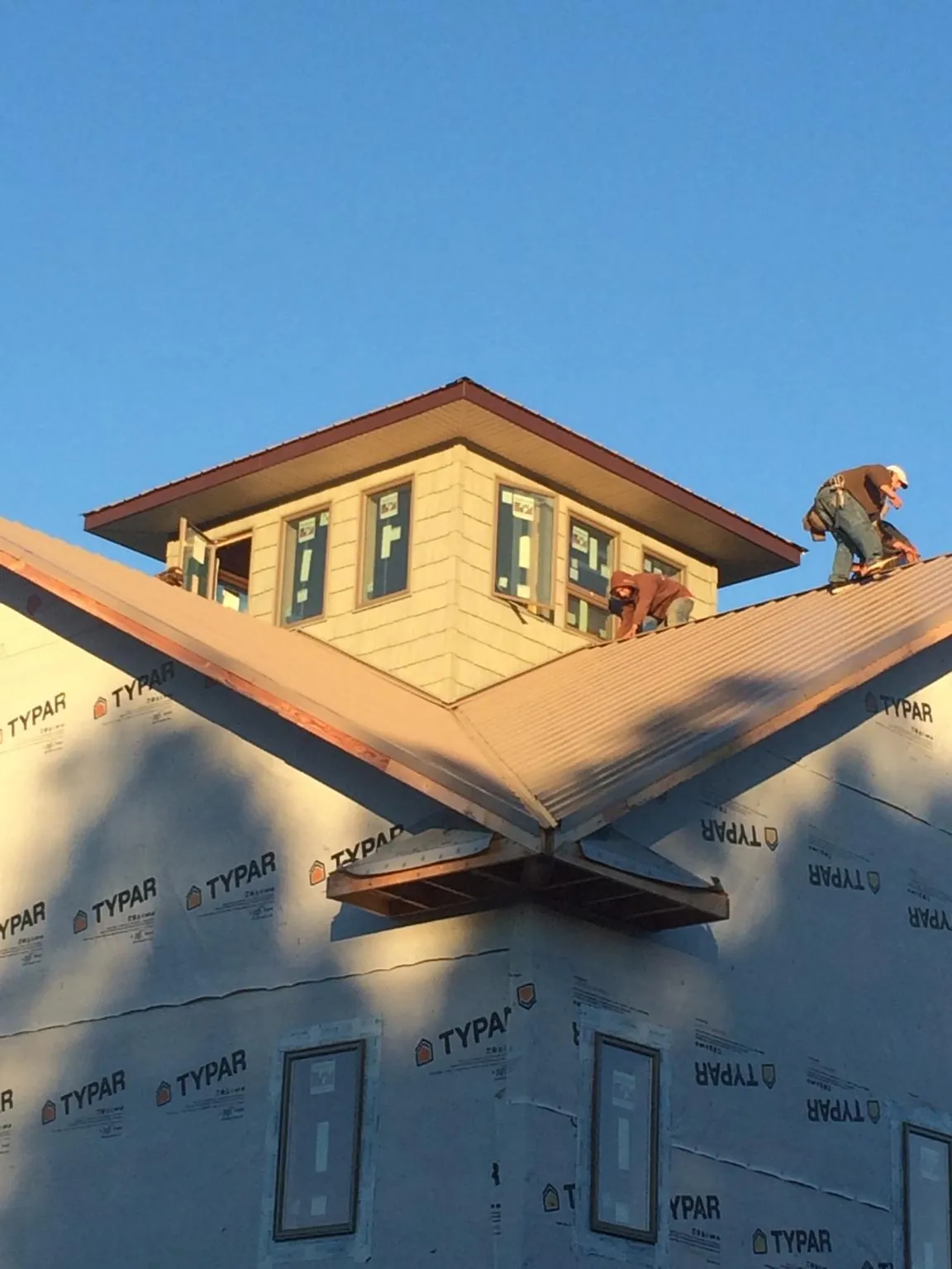 Roofers working around a rooftop cupola on a new metal roof at sunset — Roof Waterproofing in Zapata by Roofing Brothers